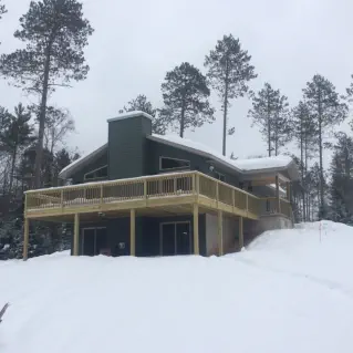 large rock chimney inside of home with log beams