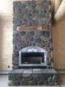 large rock chimney inside of home with log beams